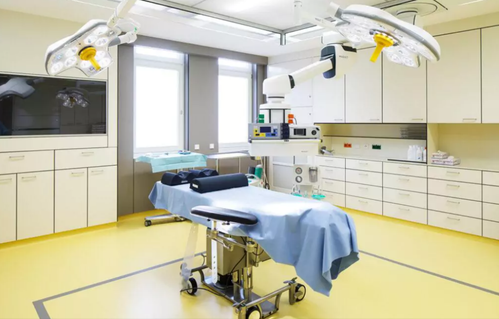 Operationsraum mit Liebe und blauem Tuch darüber auf gelbem Fußboden. Darüber eine große Operationslampe