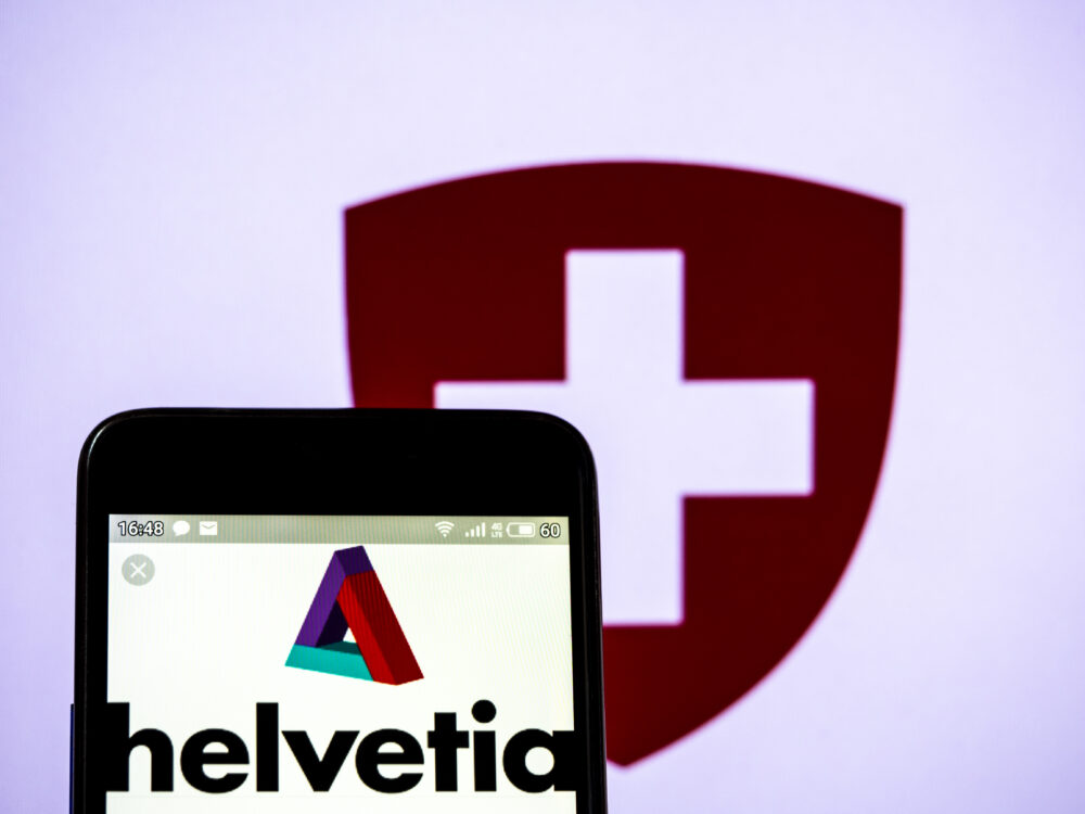 Helvetia Logo am Handy und die Flagge der Schweiz im Hintergrund