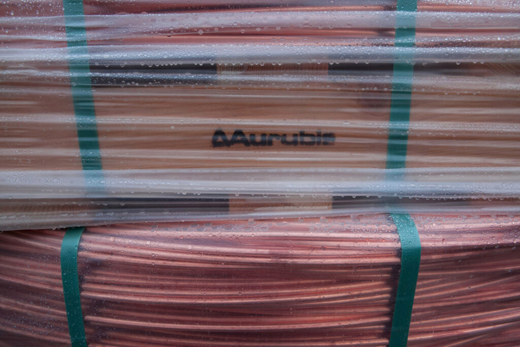 Aurubis Logo hinter einer Verpackung von Kupferdrähten