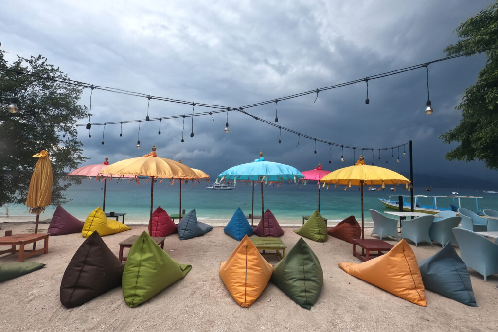 viele bunte Sitzsäcke an einem Strand mit bunten Sonnenschirmen