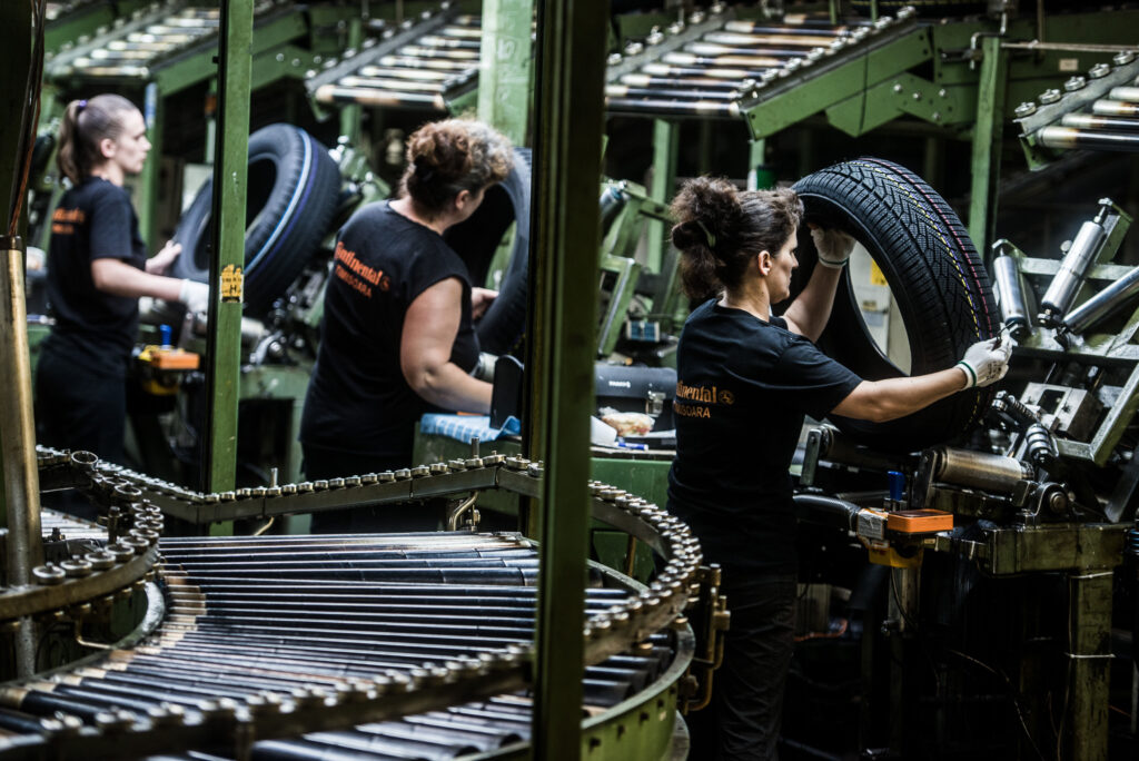 Frauen die bei Continental in einer Fabrik arbeiten und Reifen vor sich haben