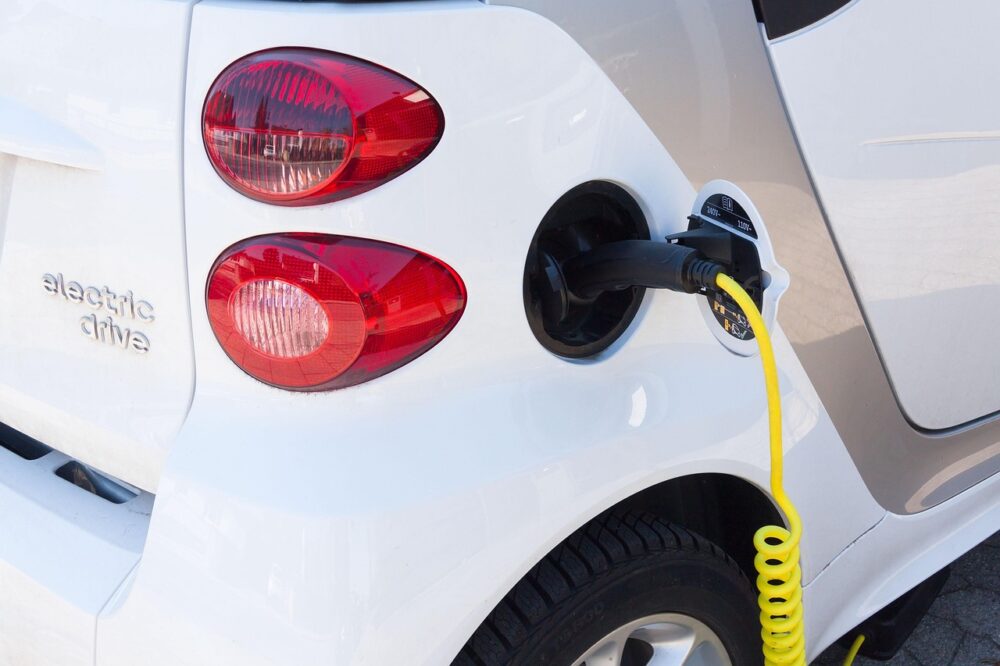 Ladekabel an einem Elektroauto auf einem Parkplatz, Symbolbild für den steigenden E-Auto Marktanteil in der EU – Foto: stux / Pixabay