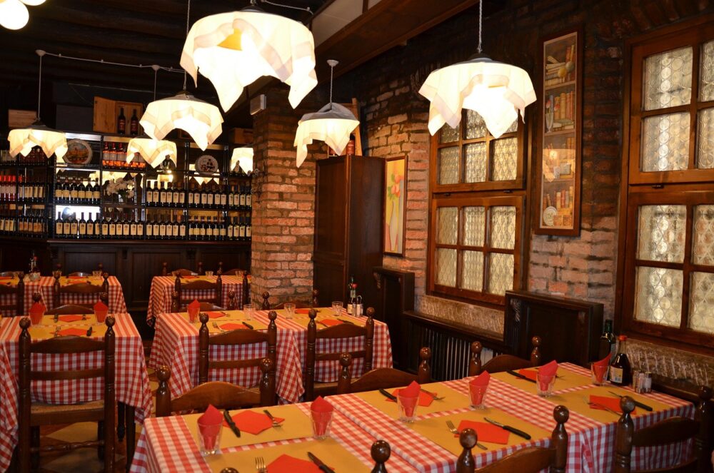 Das Bild zeigt ein italienisches Restaurant mit warmem Licht, wie es für die vom L'Osteria-Gründer mitgeprägte Gastronomie typisch ist – Foto: aldonahawthorne / Pixabay