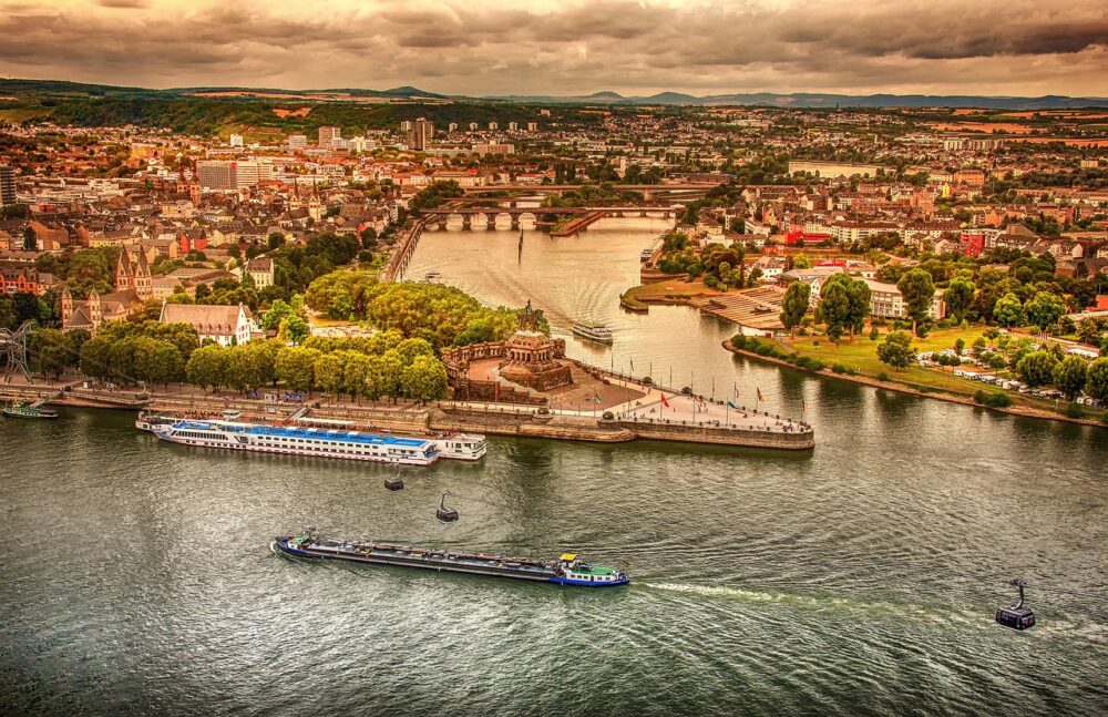 Ein Frachtschiff fährt bei Niedrigwasser am Rhein über einen Fluss mit deutlich sichtbarem, abgesenktem Wasserstand – Foto: analogicus / Pixabay