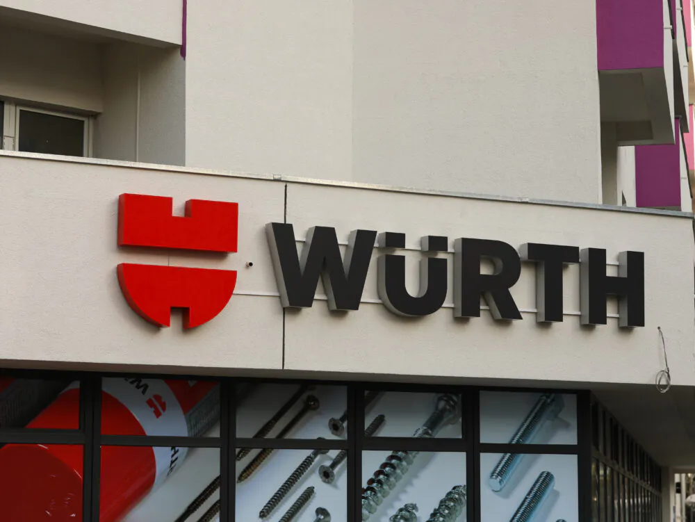 Logo von Würth in schwarz mit roten Symbolen auf einer Hausmauer über dem Eingang in eine Filiale